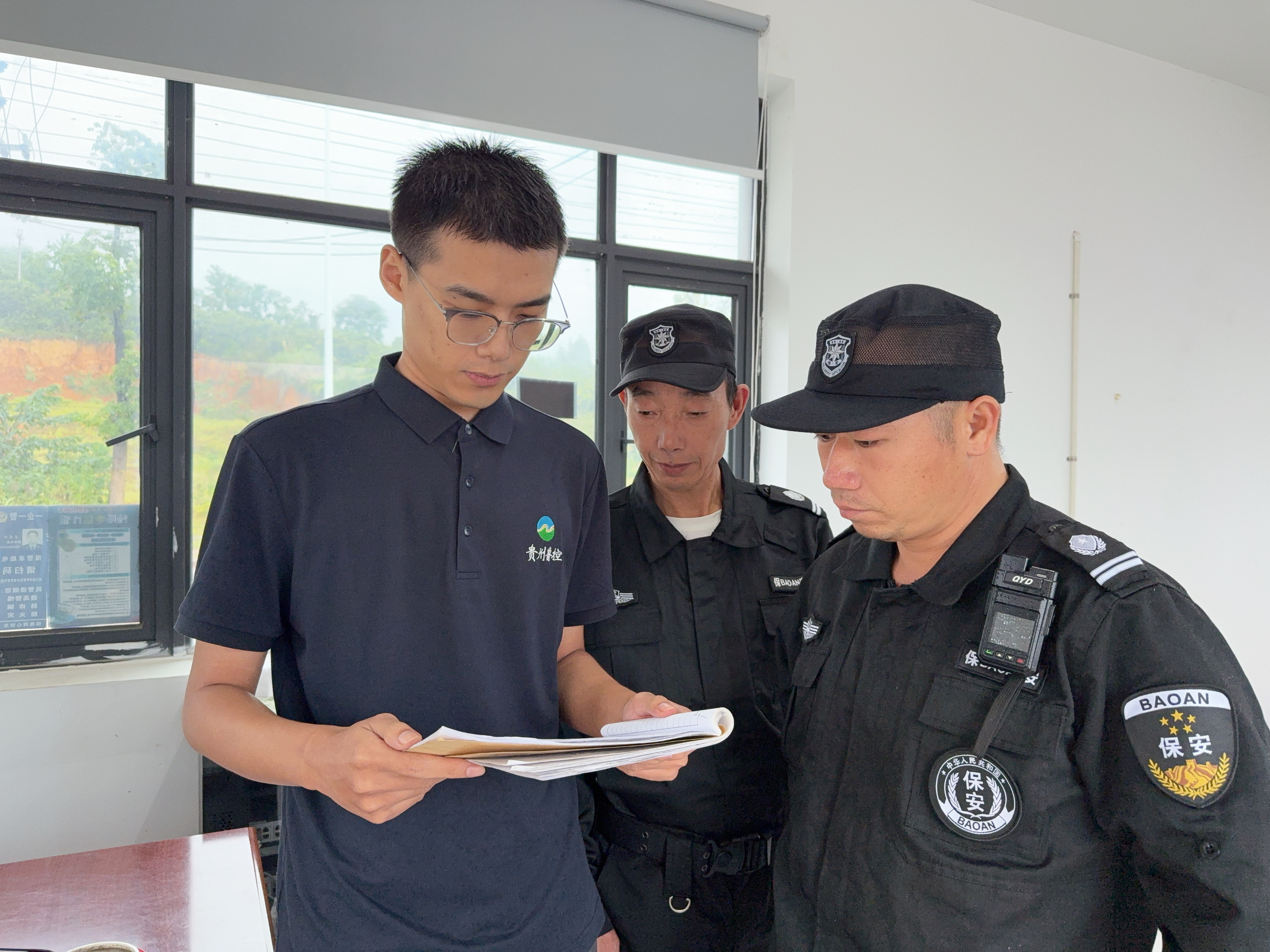圖為李鵬程檢查進(jìn)出車輛登記情況.jpg